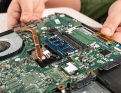 Person troubleshooting a laptop with diagnostic software and hardware tools