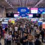 Thousands of attendees networking inside the FIL exhibition halls at Web Summit 2026 Lisbon, with startup booths and large digital screens visible throughout the venue