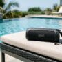 A close-up of a portable waterproof speaker sitting safely near a swimming pool edge.
