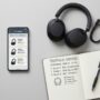 Modern wireless headphones and a smartphone on a clean grey desk.